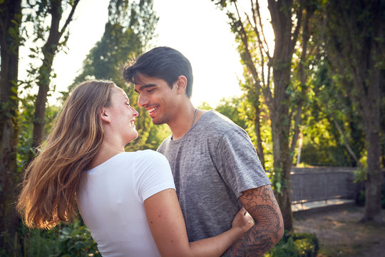 Happy young couple embracing and kissing in a park in summer