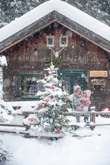 Austria, Altenmarkt-Zauchensee, mother with little son decorating Christmas tree at wooden house