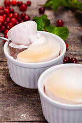Souffle with cranberries in white ramekin on wooden rustic table. Close up