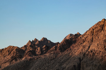 Veduta di un picco che si intravede in lontananza, tutto attorno le rosse montagne del deserto in Giordania