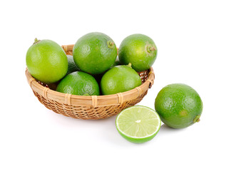 whole and half cut fresh lime in bamboo basket on white background