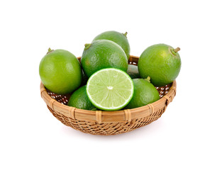 whole and half cut fresh lime in bamboo basket on white background