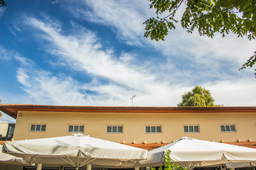 cafe restaurant  exterior patio place small building and umbrellas top with summer blue sky, copy space 