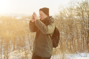 Man takes a picture on mobile phone in the steppe on a cold winter day