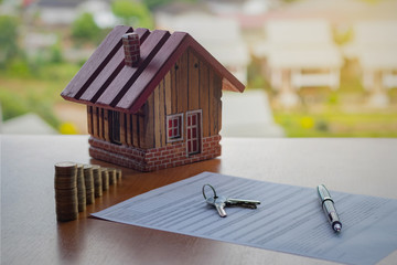 Home loan and Business investment concept. Closeup application form of Mortgage loans, pen, key, calculator and model wooden house with coins stack.