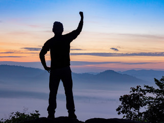 Aerial view Silhouette man standing on top of mountain to enjoy the mist in winter morning, travel and with success.