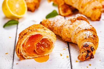 Croissants with lemon jam on white wooden background. Close up