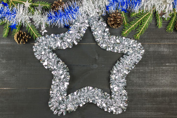 A Christmas composition. Tisnel star, spruce branch, cones on black wooden background