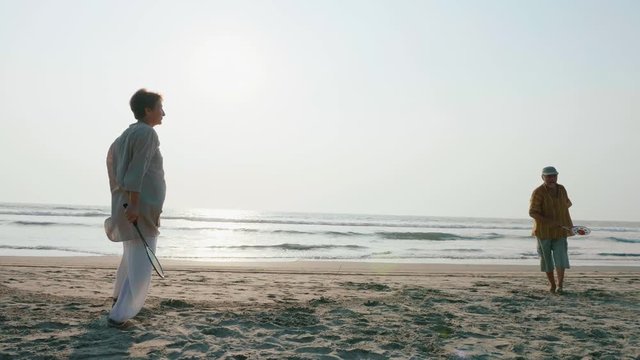 Active senior couple playing tai chi ballon ball at the beach in slow motion.