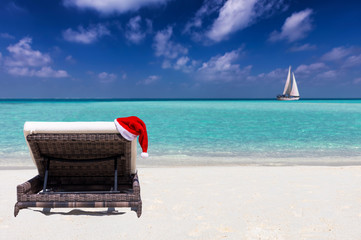 Weihnachtsurlaub Konzept: rote Weihnachtsmütze an einer Sonnenliege am tropischen Strand
