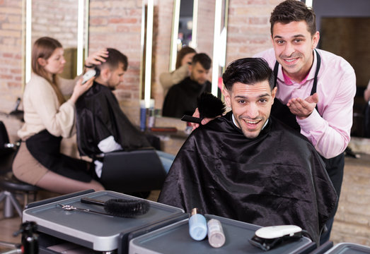 Hairdresser finished haircut of pleased man client