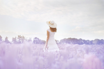 beautiful girl in a white dress and hat in a field of purple flowers - Powered by Adobe