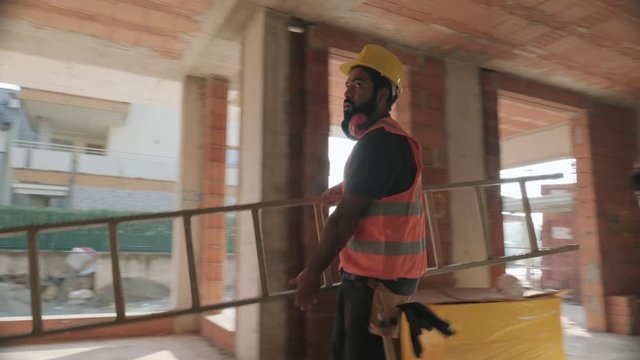 People working in construction site. Men at work in new house inside apartment building. Team of professional workers using tools and equipment