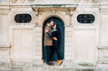 Fototapeta na wymiar Beautiful young brunette couple stand in the arch in the doors of an old building