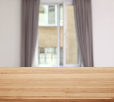 Wooden table in front of window with curtains indoors