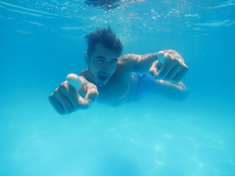 Handsome young man swimming in pool, underwater view