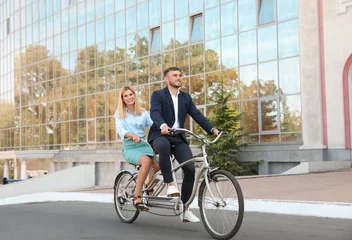 Tuinposter Couple riding tandem bike on city street © New Africa