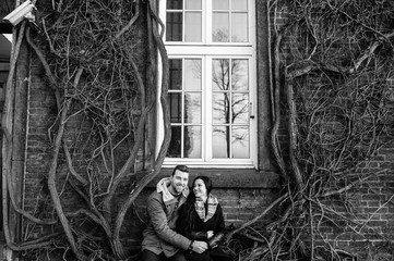happy couple sit on a vine near a brick building