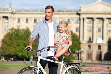 Obraz premium Happy father and his daughter with bicycle outdoors on sunny day