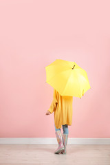 Woman with yellow umbrella near color wall
