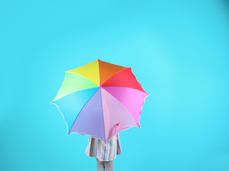 Little girl with rainbow umbrella on color background