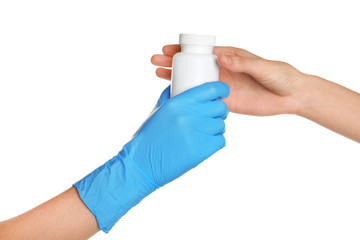 Doctor in medical glove giving bottle of pills to patient on white background