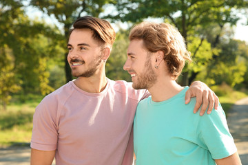 Obraz premium Portrait of happy gay couple smiling in park