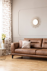 Real photo of a leather couch and elegant lamp in a living room interior