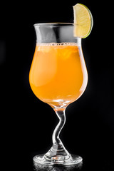 beautiful orange cocktail with ice garnished with an orange slice in a Hurricane glass isolated on a black background. close up. dark background