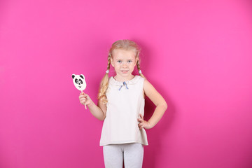 Cute little girl with candy on color background