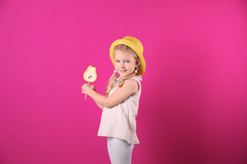 Cute little girl with candy on color background
