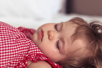 Close up portrait of a beautiful nine month old baby girl sleeping on blurred background. Sleeping child face. Cute infant kid. Child portrait in pastel tones. Selective focus.