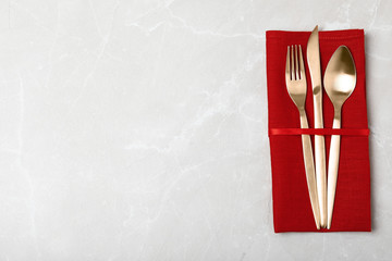 Napkin with golden cutlery on table, top view. Space for text