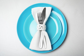 Plates with cutlery and napkin on light background, top view. Festive dinner setting