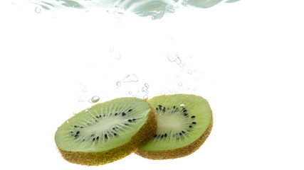 Naklejka na ściany i meble Slices of kiwi rings thrown into the water. View from under the water
