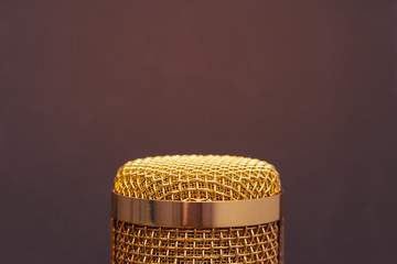 Close-up the head of condenser gold microphone in bottom of the picture. Artistic style.