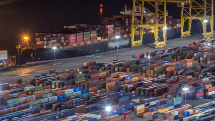 Seaport and loading docks at the port with cranes and multi-colored cargo containers night timelapse