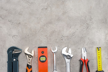 flat lay with row of various tools on concrete surface