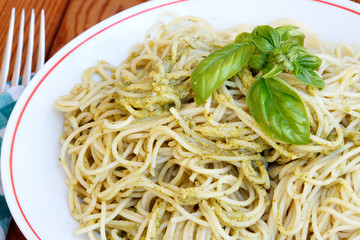 Spaghetti with pesto sauce and basil garnish