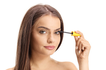 Beautiful young woman applying mascara