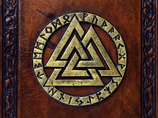Vintage leather book with gilded Odin's symbol, surrounded with runes. English translation of the runes is: A B C D E F G H I J K L M N O P Q R S T U V W X Y Z