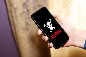 white pirate skull with word, hacking on smartphone screen