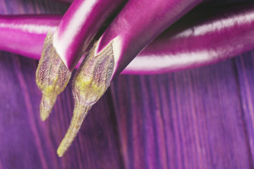 Long and slim asian finger eggplant on a purple background. Top view, copy space