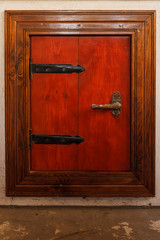 Obraz premium Wooden door of red color with metal hinges of black color. Built-in door