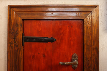 Wooden surface of red color with metal hinges of black color, and door handle. Close-up....