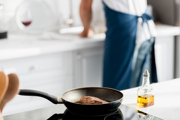 close up view of steak on pan and bottle of oil