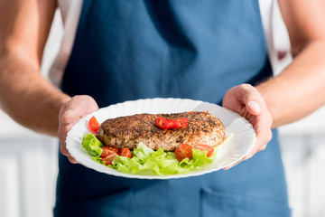 partial view of male hands with cooked meat on plate