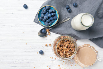 Granola muesli, milk and ripe blueberries, healthy breakfast concept, wooden background, top view