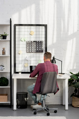 back view of man sitting at workplace at home office