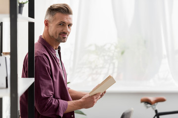 Fototapeta premium man standing with book in hands at home office